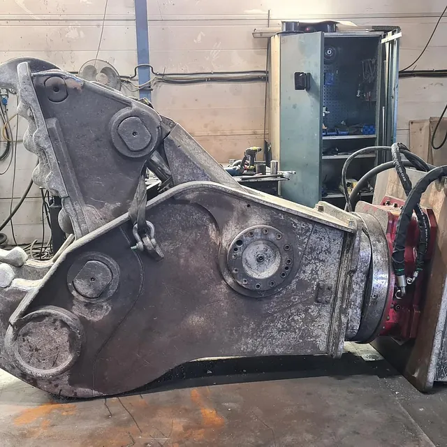 Stor hydraulisk klype ligger klar for vedlikehold i verksted