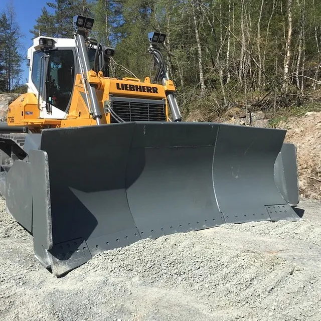 Stor bulldoser med rett skjær står parkert på grusvei i skogsområde